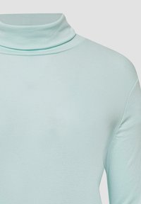 Jasnozielony golf wykonany z miękkiego, elastycznego materiału. Posiada złożony kołnierz oraz długie rękawy o gładkiej, jednolitej fakturze.