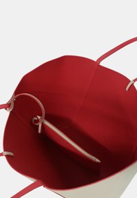 Borsa tote in pelle rossa con interno liscio e tasca con zip; presenta due manici attaccati a un'ampia apertura.