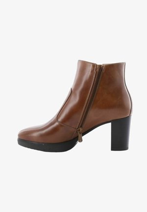 Bruine leren enkelboot met een zijknop, ronde neus en een zwarte chunky hak. Glad textuur en slank ontwerp met minimale details.