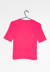 Růžový žebrovaný top s krátkým rukávem a kulatým výstřihem, zavěšený na černém háčku. Má strukturovanou tkaninu a přiléhavý střih.