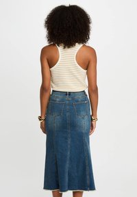 Light-colored striped tank top with a racerback design paired with a long denim skirt featuring a fitted waist and frayed hem.