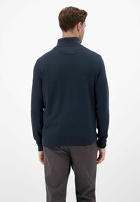 Granatowy sweter z wysokim kołnierzem, ściągaczami na mankietach i u dołu, charakteryzuje się gładką teksturą i luźnym krojem. Widok z tyłu ukazuje minimalne detale.