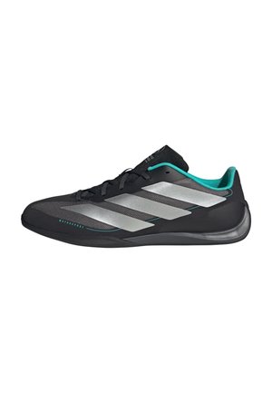 Baskets noires avec bandes argentées, doublure intérieure turquoise et semelle basse profilée, conçues pour les activités de sport automobile.