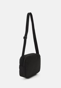 Borsa a tracolla rettangolare nera con superficie liscia e testurizzata, tracolla regolabile e chiusura con zip. Design compatto e minimalista.