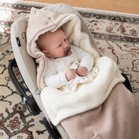 Mjuk beige och krämfärgad babyfilt med huva, som har en texturerad yta och sitter tätt runt ett sittande spädbarn i en gynna.