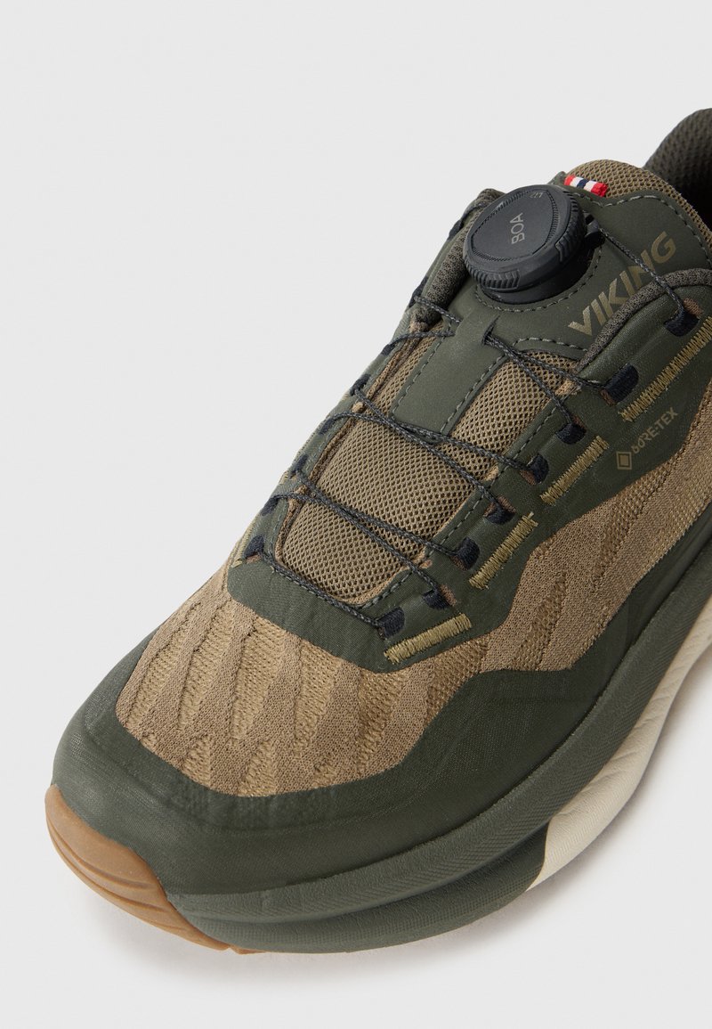 Zielono-beżowe buty do wędrówek z siateczkową cholewką, gumową podeszwą i systemem sznurowania Boa. Posiadają teksturowany wzór oraz oznaczenie Gore-Tex z boku.