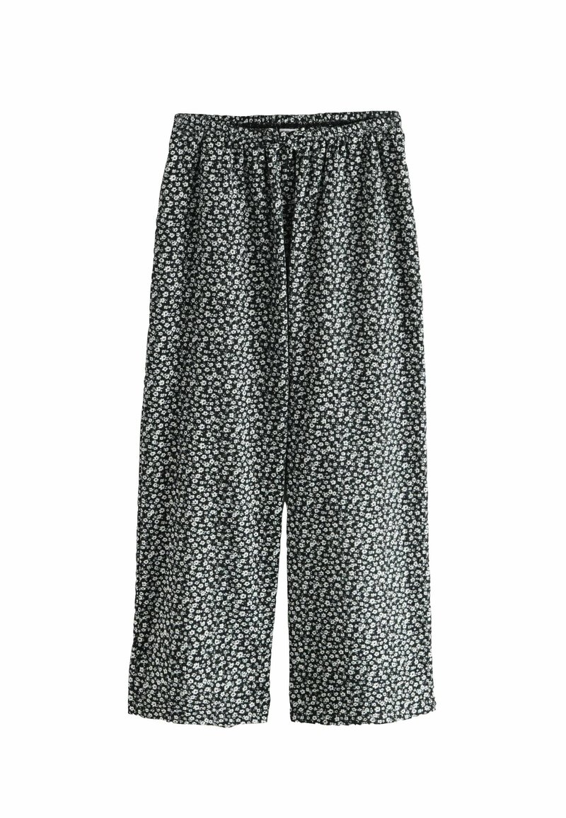 Pantalones de pierna ancha con estampado floral negro y cintura elástica, que presentan pequeñas flores blancas y una textura ligera y suave.