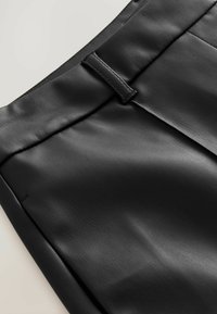 Pantaloni in pelle nera con una texture liscia e una leggera lucentezza, con fronte piatto, dettagli in vita e pieghe strutturate.