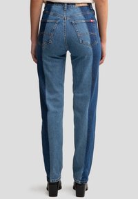 Hoge taille blauwe jeans met verschillende tinten denim, voorzien van twee achterzakken en een rechte pijp met een gladde textuur.