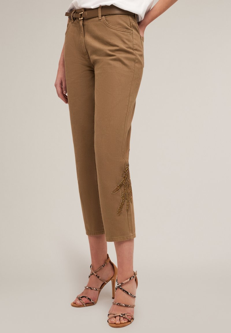 Tan cropped trousers met een aansluitende taille en zijzakken, voorzien van een decoratief kraaldecor bij de zoom. Gecombineerd met gestreepte hoge hakken sandalen.