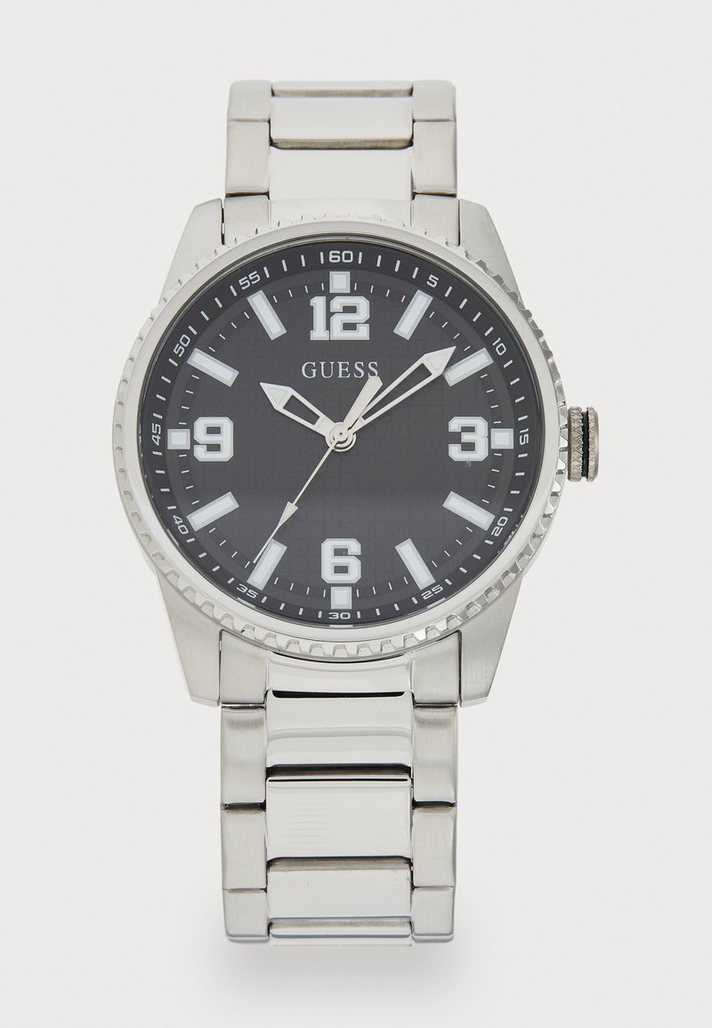 Montre en acier inoxydable argenté avec un cadran noir, de grands index horaires numériques et un bracelet en maillons argentés. Présente une lunette texturée.