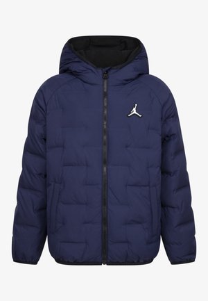 Veste matelassée bleu marine avec capuche, fermeture éclair devant, poches latérales et petit logo Jumpman blanc sur la poitrine gauche.