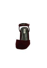 Scarpa decolleté in velluto bordeaux con tacco alto, punta quadrata e cinturino alla caviglia, caratterizzata da un interno nero e un design minimalista.
