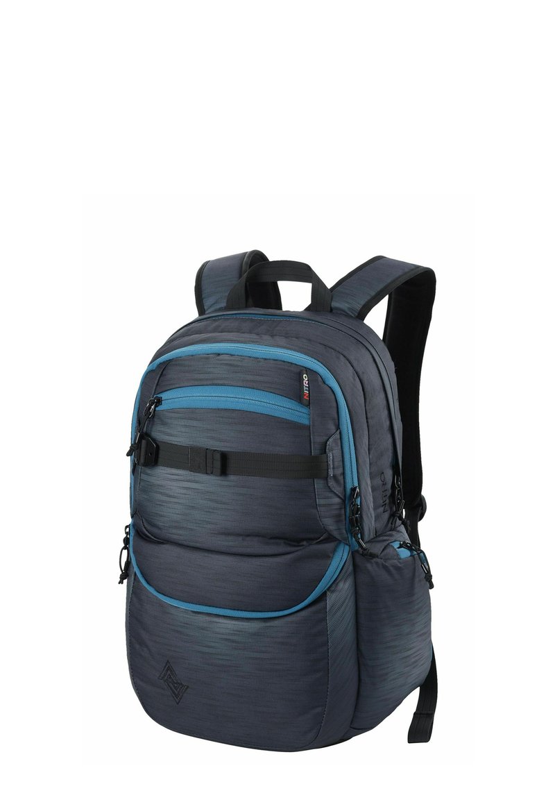 Mochila de tela gris con acentos azules, múltiples bolsillos con cremallera, espalda y correas acolchadas, y un diseño texturizado. Cuenta con hardware ajustable.