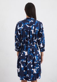 Abito blu e bianco con motivo, maniche lunghe, vita aderente e gonna plissettata. Realizzato in tessuto morbido con una superficie liscia.