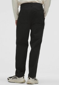 Pantaloni cargo neri realizzati in tessuto resistente, con due grandi tasche posteriori, vestibilità rilassata e design a gamba dritta.
