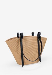 Bolsa de tote de paja trenzada con forma cónica, color beige y asas de cuero negro. Presenta dos correas superiores y un hardware mínimo.