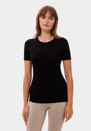 T-shirt nera a maniche corte realizzata in tessuto liscio, con collo rotondo e design aderente, abbinata a leggings beige chiaro.