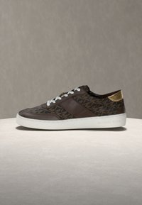 Rjav patinasti čevelj z belimi vezalkami, usnjenim zgornjim delom, zlatim poudarkom na peti in belo gumijasto podplato. Oznaka "MICHAEL KORS."