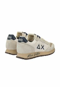 Scarpe da corsa beige con tomaia in suede e tessuto, dettagli blu scuro, logo triangolare e testo "Corri più veloce" sulla suola.