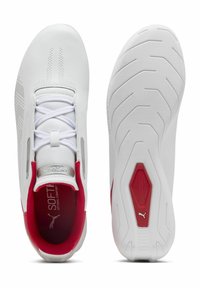 Scarpe da ginnastica bianche con una parte superiore in sintetico liscio, linguetta in rete, lacci elastici e un tallone rosso in contrasto. Suola in gomma testurizzata con scanalature.