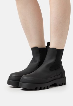 Czarne botki za kostkę z elastycznymi panelami bocznymi, masywnymi gumowymi podeszwami i teksturalnymi akcentami na obcasach. Gładki i minimalistyczny design.