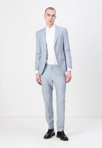 Costum ajustat de culoare albastru deschis, realizat dintr-un material neted, asociat cu o cămașă albă. Pantofii negri duc la bun sfârșit look-ul. Design simplu, croială slim.