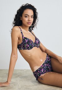 Black bikini set featuring a floral pattern in purple, pink, and green, with a twisted design on the top and adjustable side ties on the bottoms.