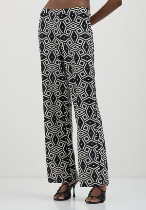 Pantaloni a gamba larga in un motivo geometrico bianco e nero; tessuto morbido con una texture liscia; vita alta; abbinati a tacchi a strappo.