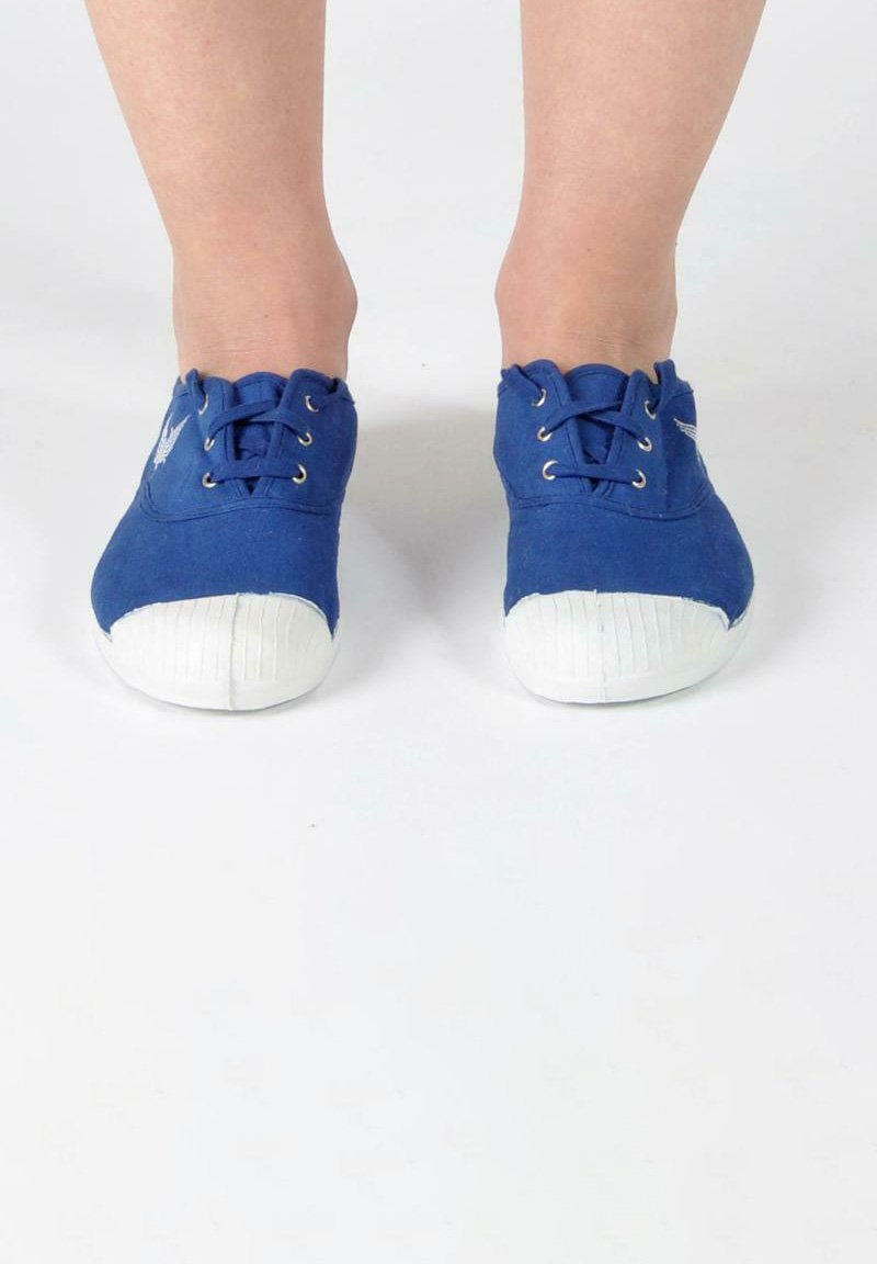 Scarpe di tela blu con punte di gomma bianche e suole testurizzate. Presentano lacci rotondi e un logo discreto sul lato.