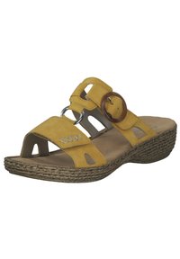 Yellow suede sandal with round brown accent, open toe, multiple cutouts, and a cork-like wedge sole. Features adjustable strap and stitching detail.