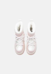 Balti un gaiši rozā ziemas zābaki ar biezām baltām kurpju kājām un pūkaino iekšējo oderi, skatīti no augšas uz vienkārša fona.