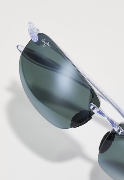 Sonnenbrille mit dunkelgrauen Gläsern, transparenten Rahmenakzenten und einem eleganten, geschwungenen Design. Mit einem Logo auf dem Glas.
