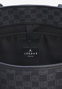 Zwarte rugzakinterieur met een patroontextiel met een subtiele "23"-ontwerp. Inclusief een label met de tekst "JORDAN" en "SINCE 1984".