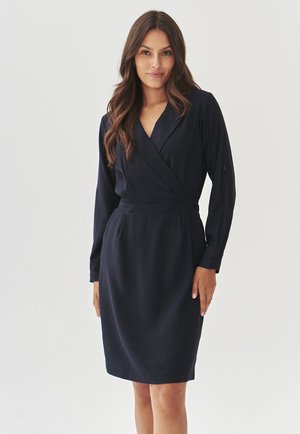 Navy blue, long-sleeve wrap dress with a collared neck, belted waist, and smooth texture. Features button cuffs and a knee-length design.
