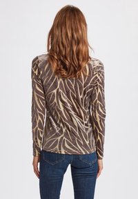 Långärmad topp i mjukt, sammetsliknande tyg med ett mönster av bruna och krämiga blad. Figurnära design med rund halsringning och slät yta.