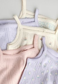 Pastelowe dzianinowe topy na ramiączkach z delikatnymi kwiatowymi wzorami i falistymi brzegami, ułożone nachodzące na siebie na jasnoszarym tle.