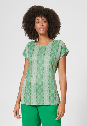 Grün gemusterte Bluse mit rundem Ausschnitt, kurzen Ärmeln und lockerer Passform. Das Design bietet abwechselnd gewellte Linien und Rautenformen.