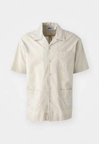 Camisa beige de manga corta con cuello, botones en la parte delantera, bolsillo en el pecho y dos bolsillos frontales con acentos de bordado floral blanco.