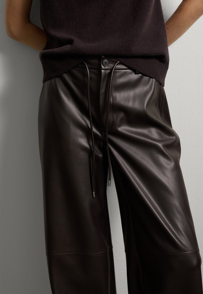 Pantalon en cuir marron avec une coupe décontractée, doté d'une taille avec cordon de serrage réglable, d'une texture lisse et de détails de couture subtils.