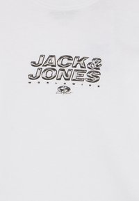 Λευκό ένδυμα με έντονο μαύρο κείμενο "JACK & JONES", μικρότερο "WORLDWIDE" από κάτω και ένα μικρό εικονίδιο γης με γραφή "core sport".