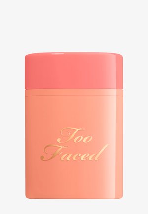 Korallen- und pfirsichfarbenes rechteckiges Make-up-Behältnis mit abgerundetem korallenfarbenem Deckel und goldenem "Too Faced" Logo auf der Vorderseite.