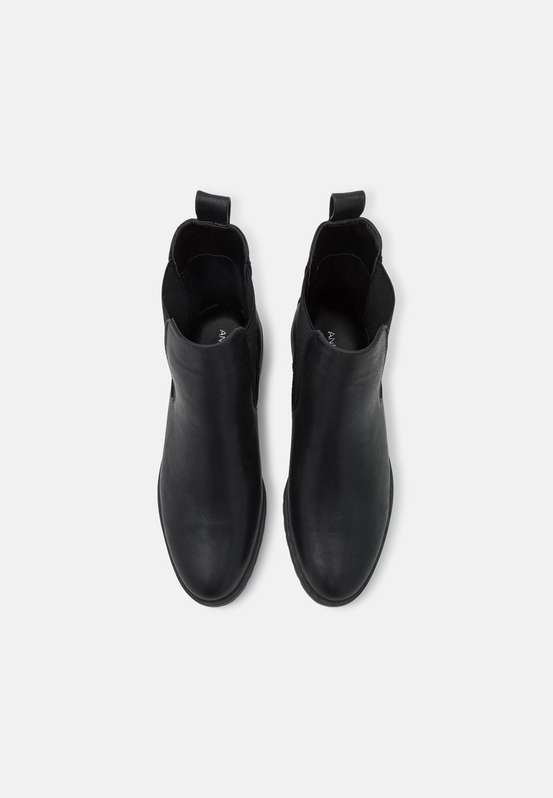 Botas de tobillo de cuero negro con una textura suave, puntera redonda, paneles laterales elásticos y tiradores para un fácil calzado. Diseño simple y minimalista.
