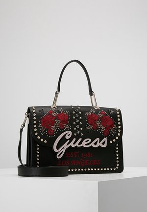 Czarna torebka Guess z czerwonymi, haftowanymi różami, srebrnymi ćwiekami, górnym uchwytem i odpinanym paskiem na ramię, z napisem „Guess EST. 1981 LOS ANGELES.”