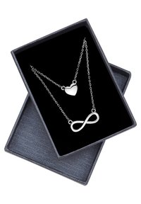 Silverhjärtan och oändlighetssymbolhalsband uppvisade i en öppen svart smyckeslåda med ett strukturerat mörkgrått lock under.