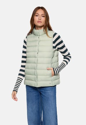 Chaleco acolchado verde claro con cuello alto, secciones acolchadas horizontales y bolsillos laterales, usado sobre una camiseta de manga larga a rayas blancas y negras.