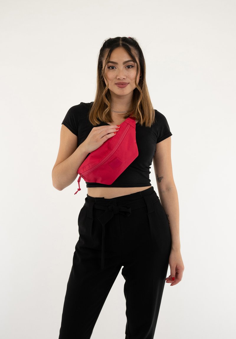 Borsa in vita rossa con un design elegante, realizzata in tessuto liscio, caratterizzata da una forma diagonale e una chiusura con cordoncino regolabile.