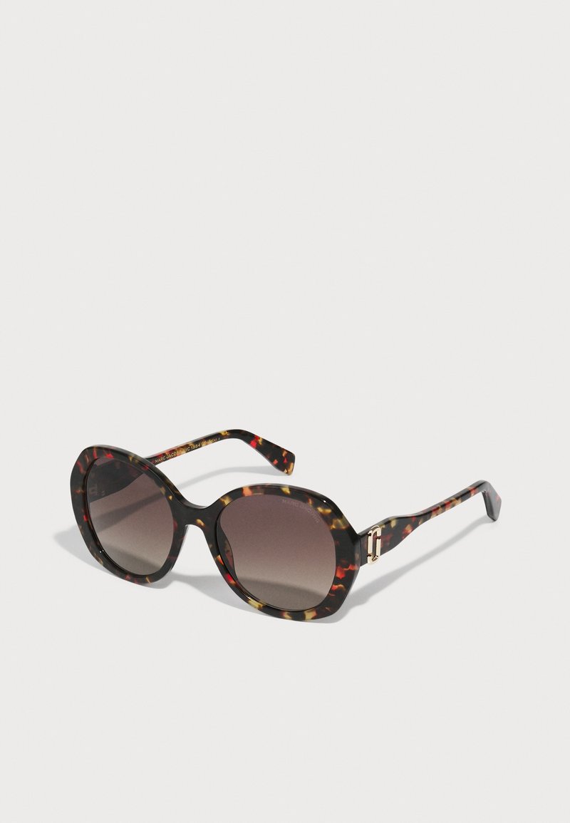 Runde Sonnenbrille mit einem Schildpatt-Muster in Schwarz, Braun und Rot, ausgestattet mit Verlaufslinsen und goldfarbenen Hardware-Akzenten.