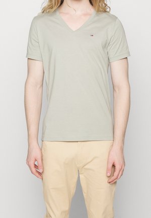 Lichtgroen V-hals T-shirt van zacht materiaal, met korte mouwen en een klein logo-accent op de borst, gecombineerd met beige broeken.