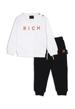 Felpa bianca con la scritta "RICH" in lettere arancioni e pantaloni della tuta neri con vita regolabile e dettaglio del logo. Materiale morbido, design casual.